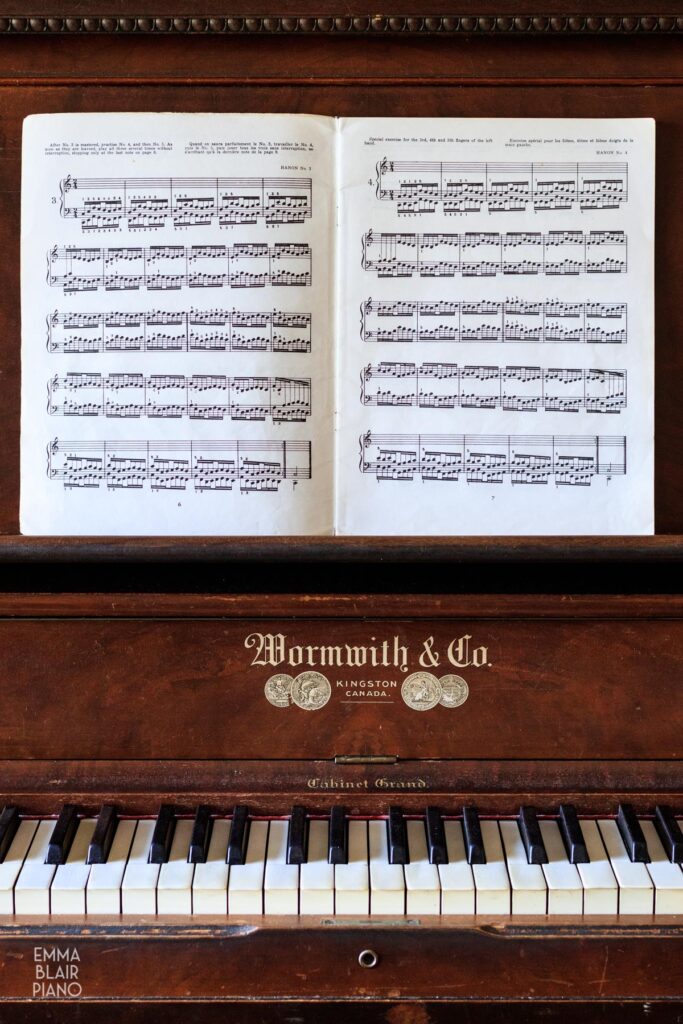 book of Hanon exercises open on a piano music stand