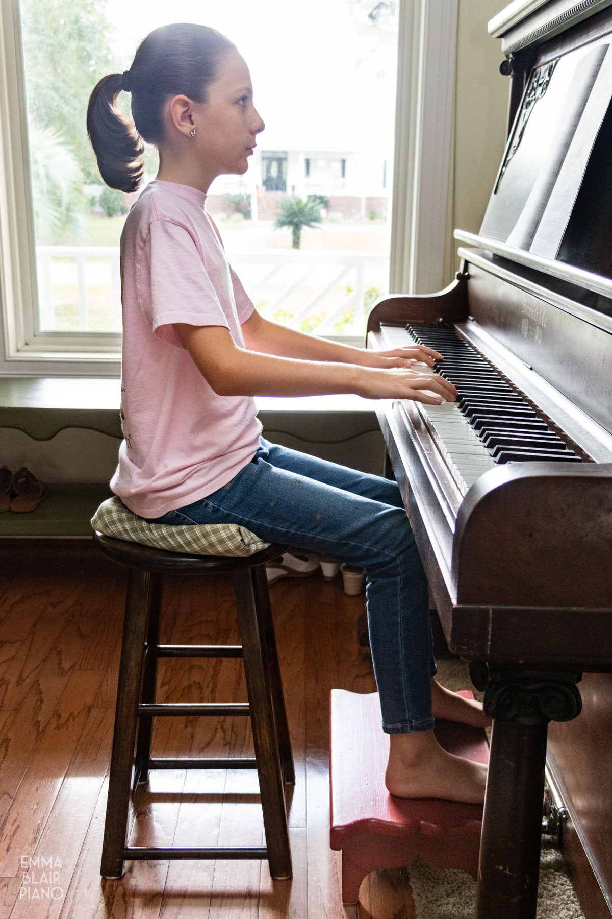 girl sitting at the piano with a footstool