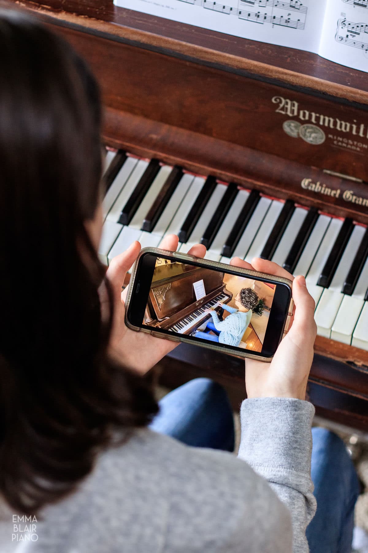 teenage girl watching a piano video on a cell phone