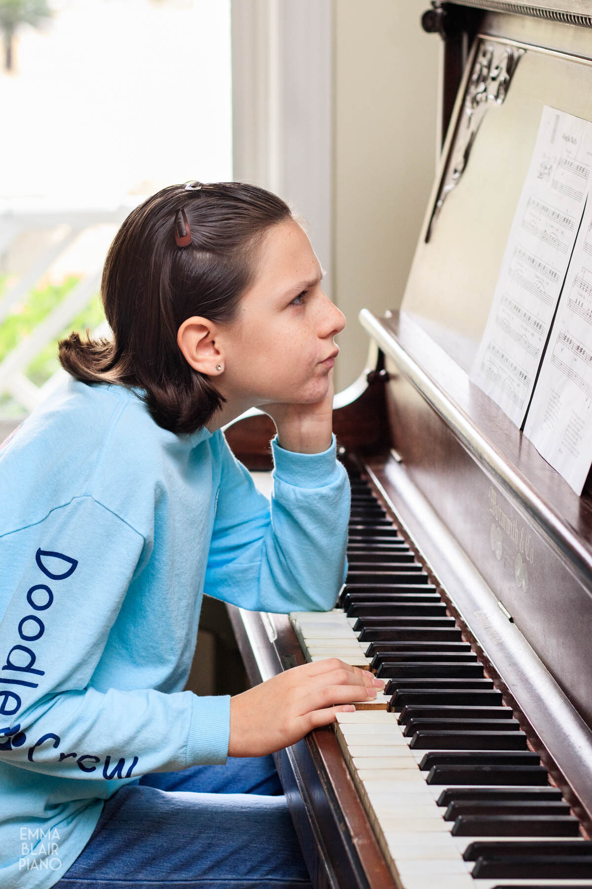 girl frowning at sheet music while playing the piano