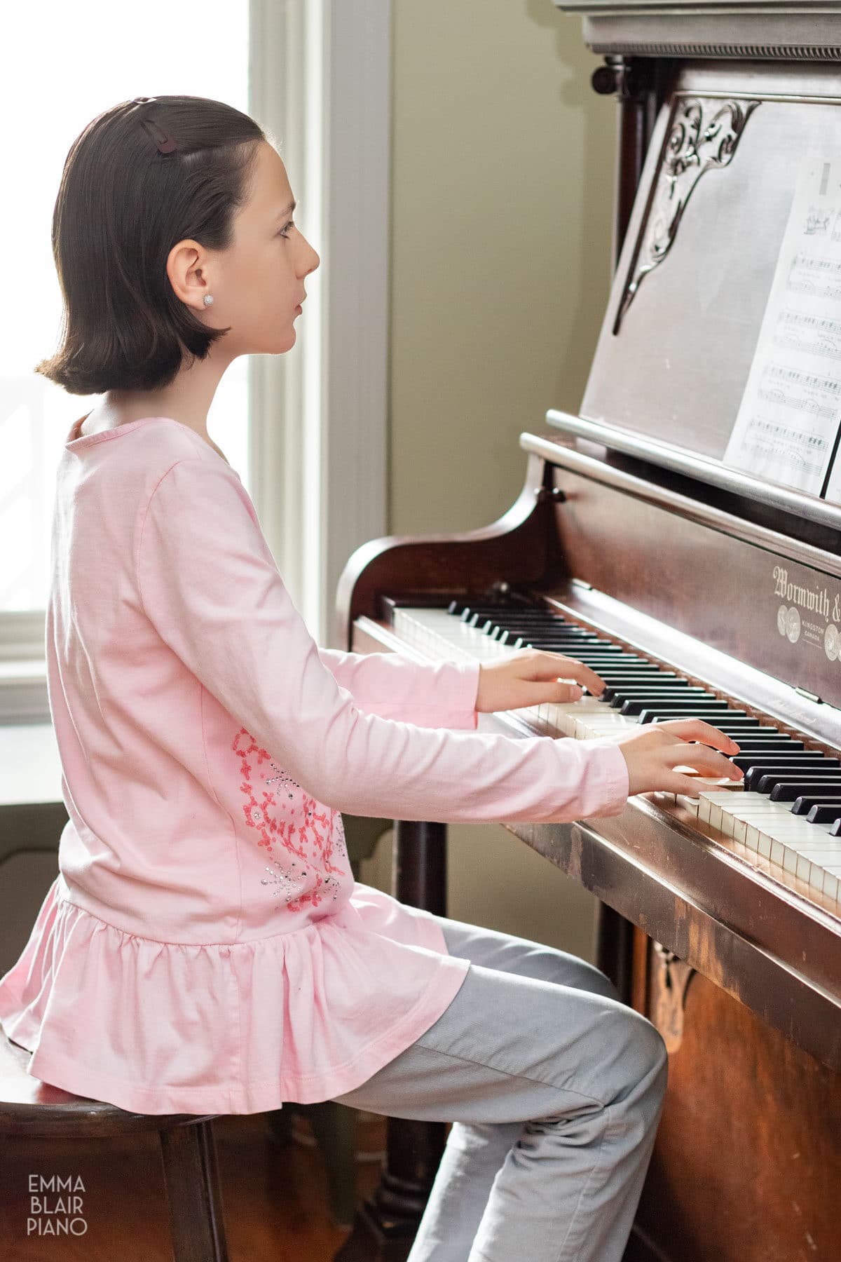 young girl playing an upright piano