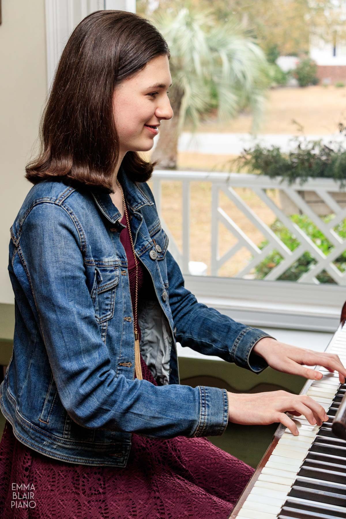 teenage girl playing the piano and smiling