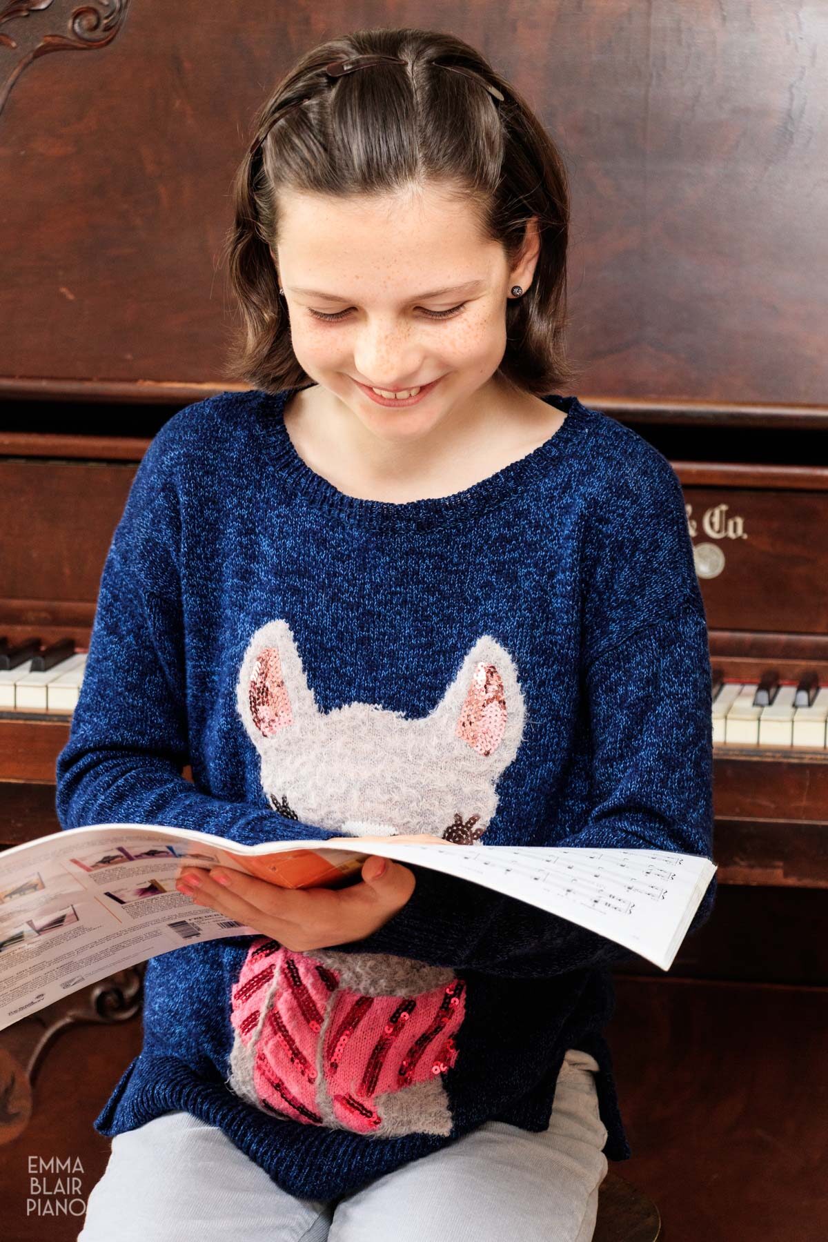 young girl smiling while holding a book of piano music