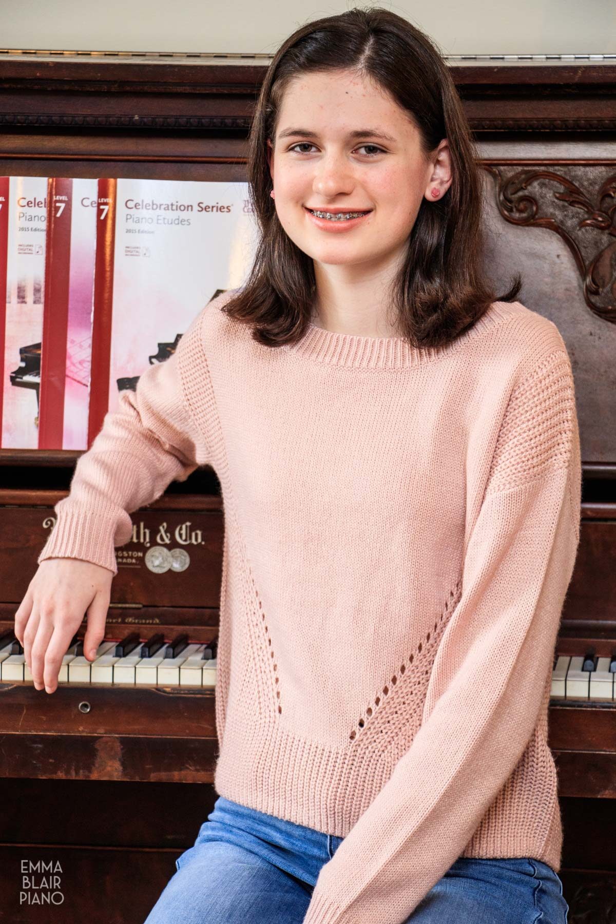 teenage girl leaning on the piano and smiling