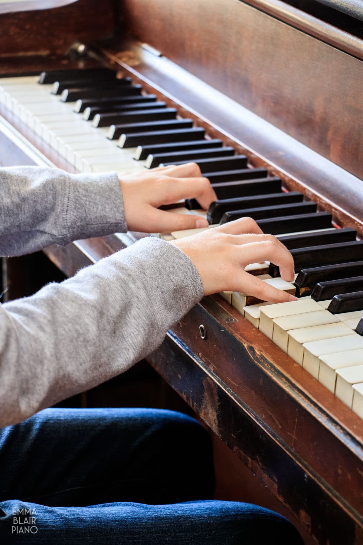 side view of a girl playing C major chords at a piano