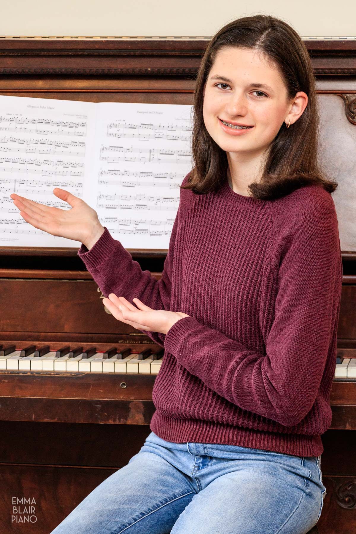 teenage girl pointing to piano music and smiling