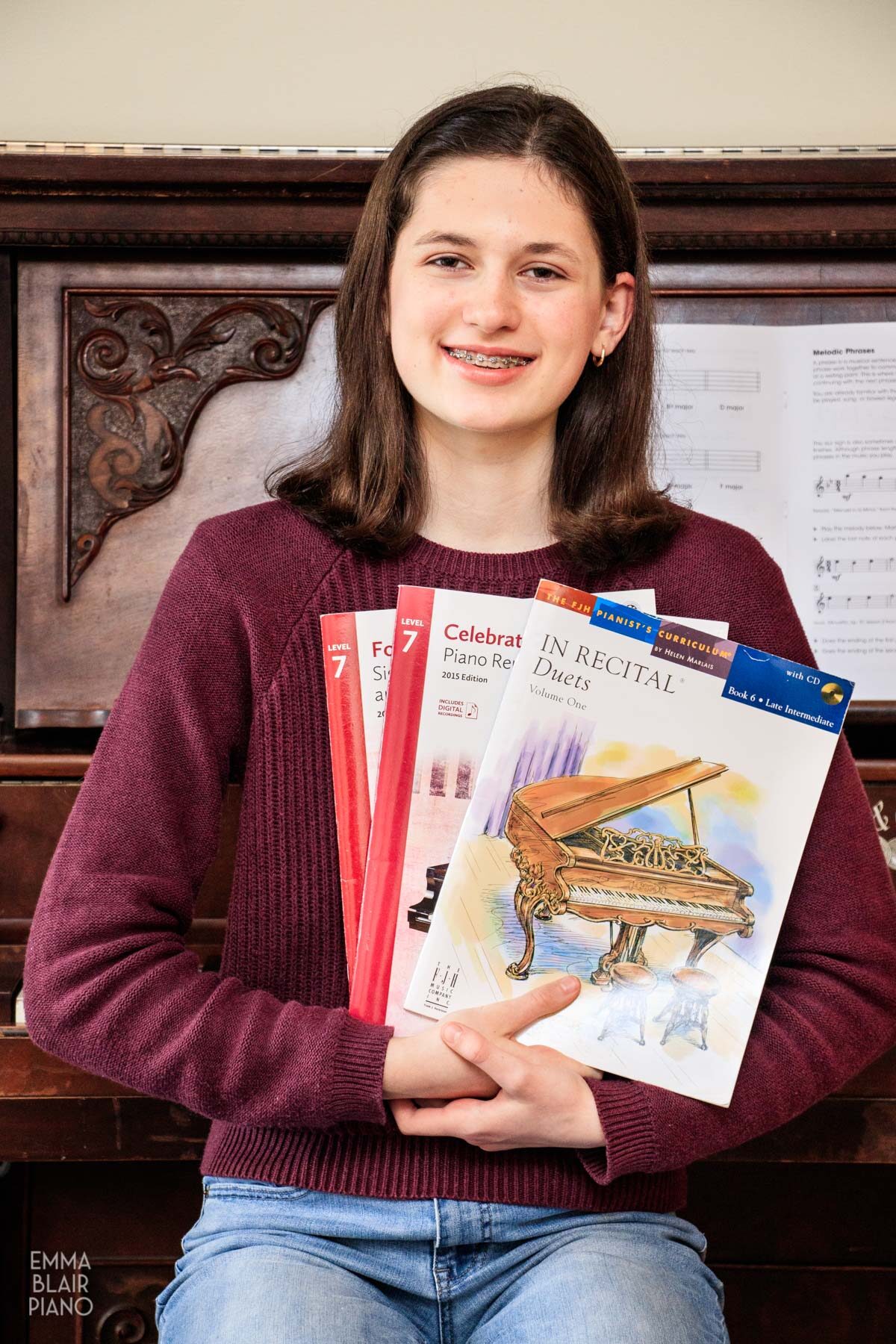 teenage girl holding piano music books and smiling