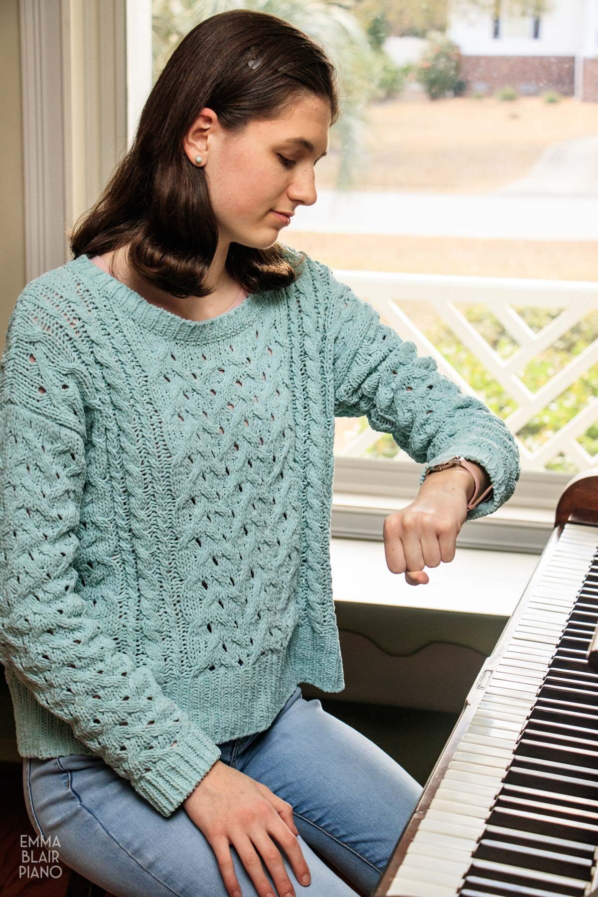 teenage girl checking her watch as she sits at the piano