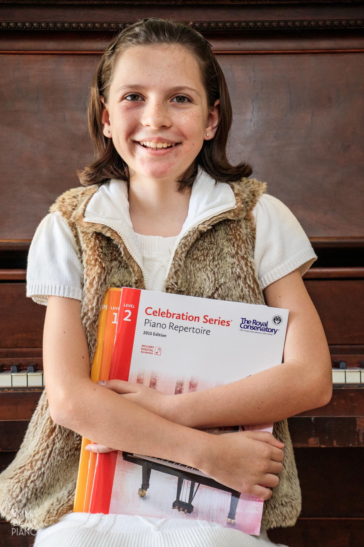 smiling girl holding a stack of piano books