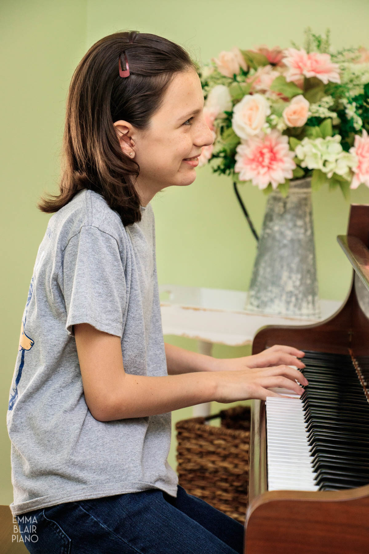 young girl smiling while she plays the piano