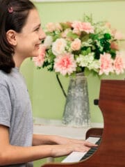 young girl playing a grand piano and smiling