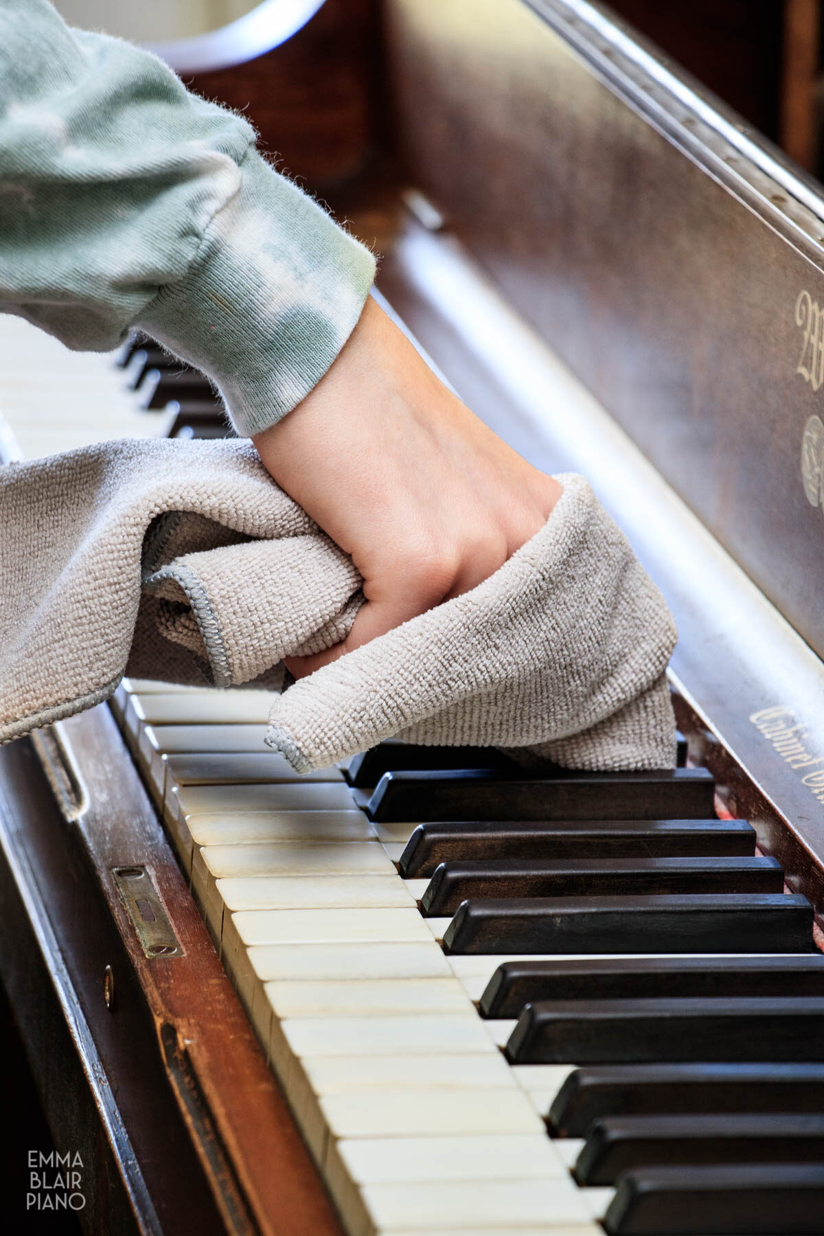 teenage girl cleaning the piano keys with a microfiber cloth