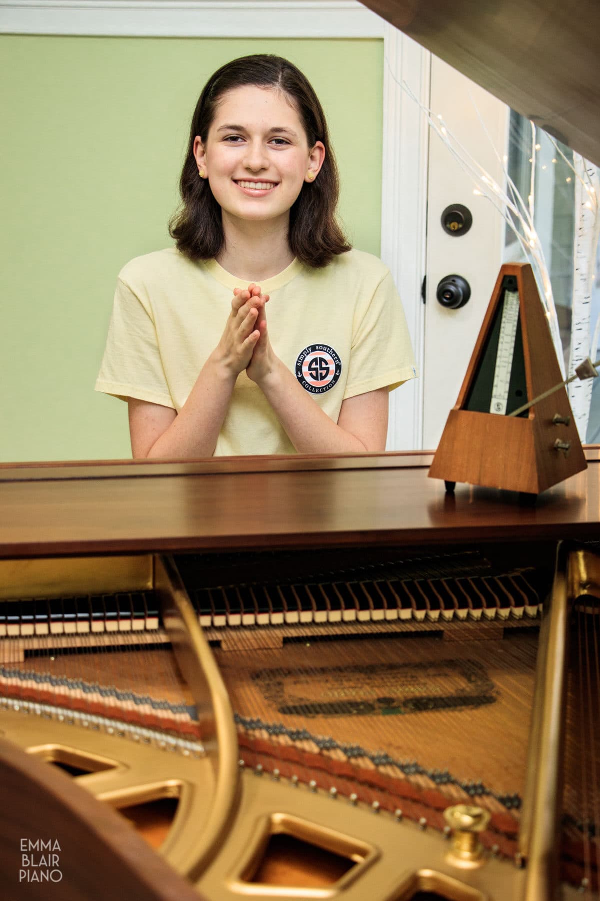 teenage girl clapping a rhythm with a metronome at the piano