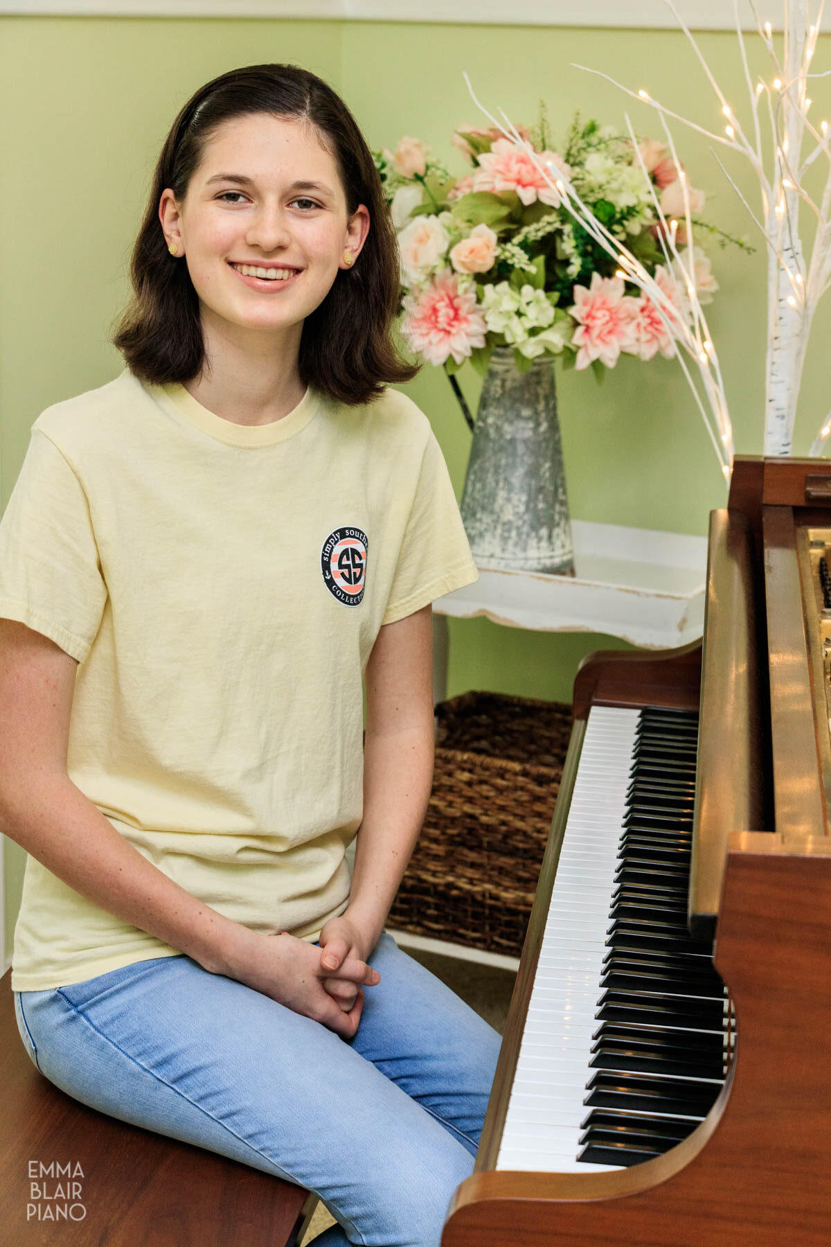 teenage girl sitting at a grand piano and smiling