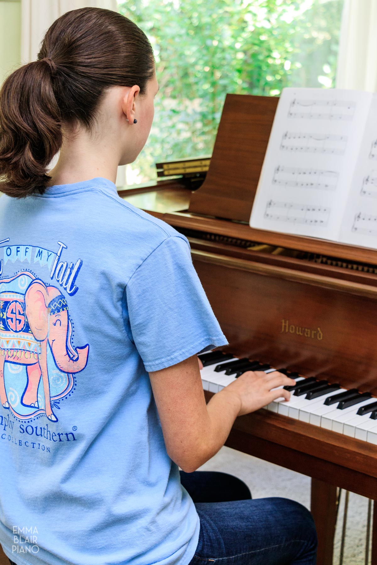 teenage girl playing a beginning piano piece on a brown piano