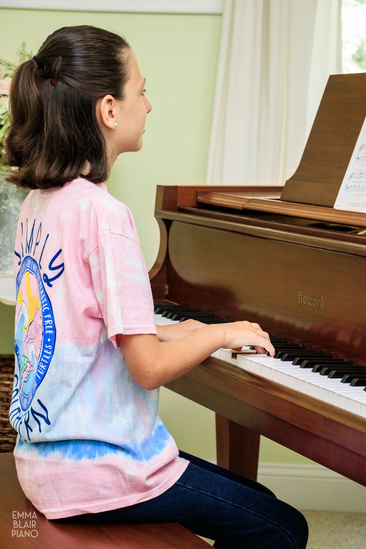 young girl playing a brown grand piano