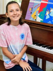 young girl sitting at a grand piano and smiling