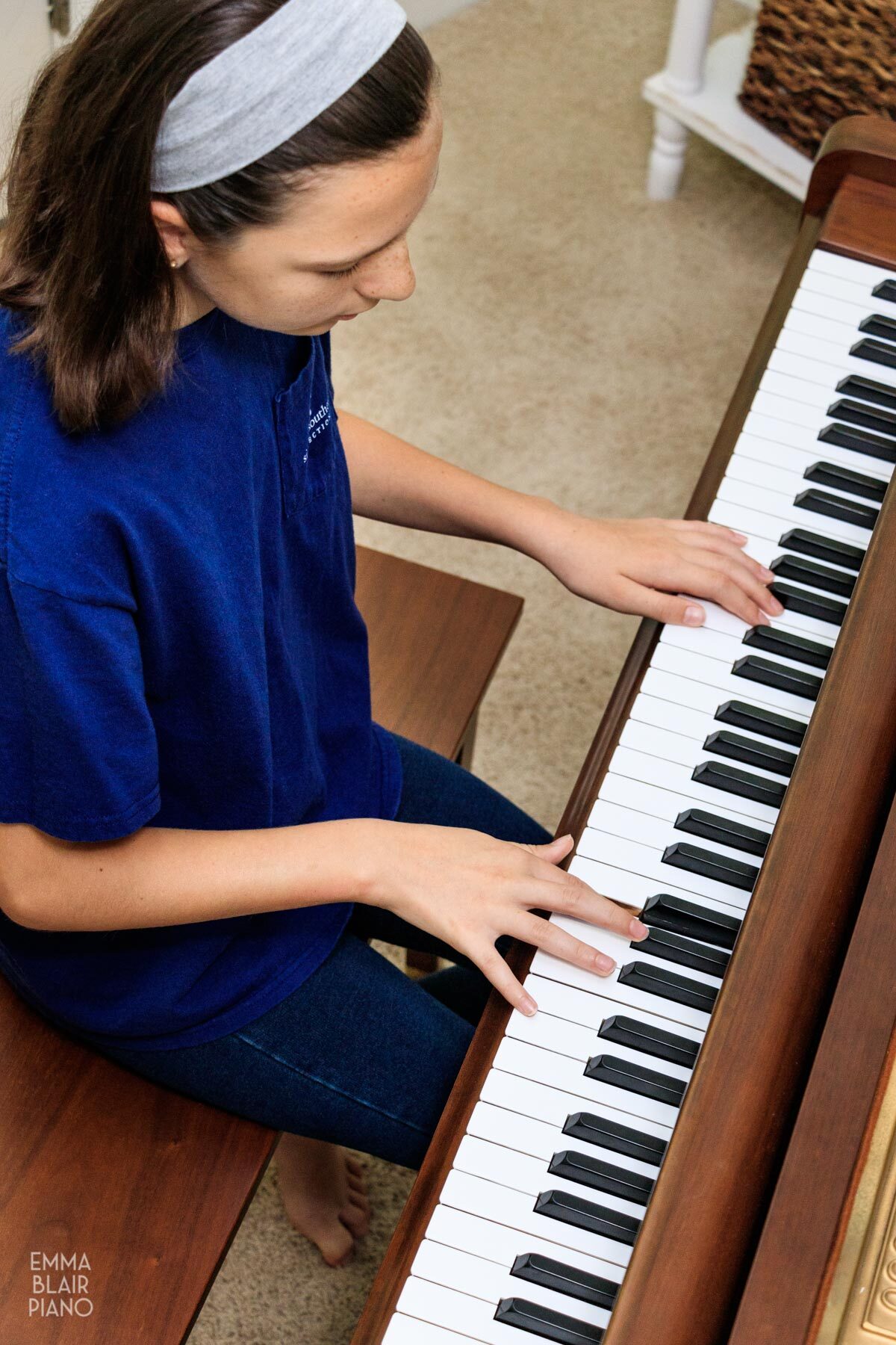 young girl playing a brown grand piano