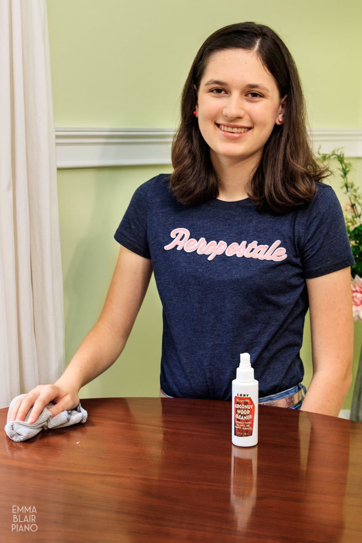 teenage girl cleaning piano lid with wood cleaner