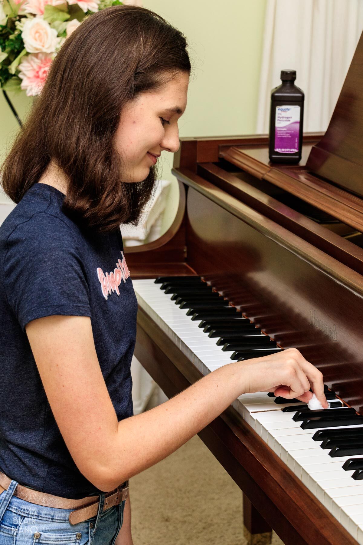 girl cleaning piano keys with hydrogen peroxide on a cotton ball