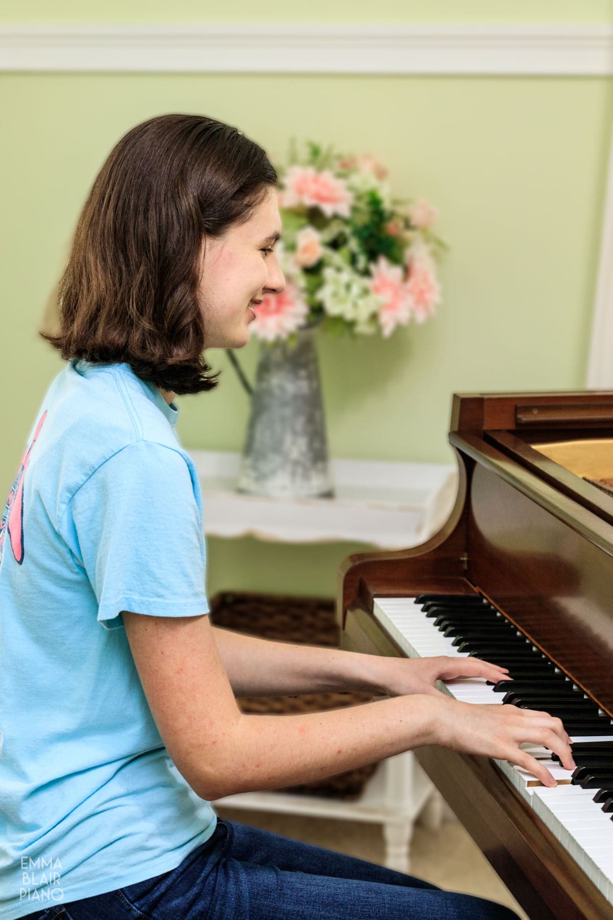 teenage girl smiling and playing a grand piano