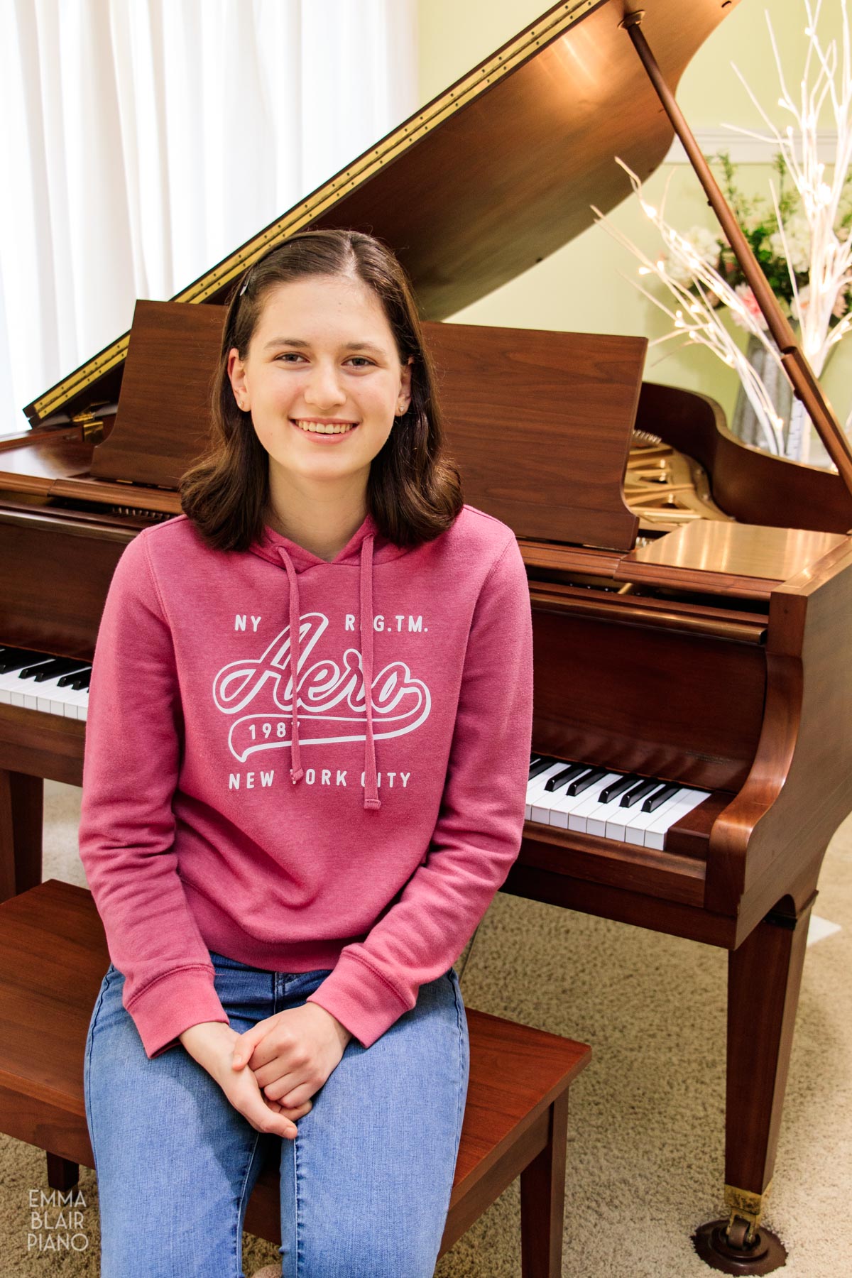 teenage girl smiling and sitting in front of the piano