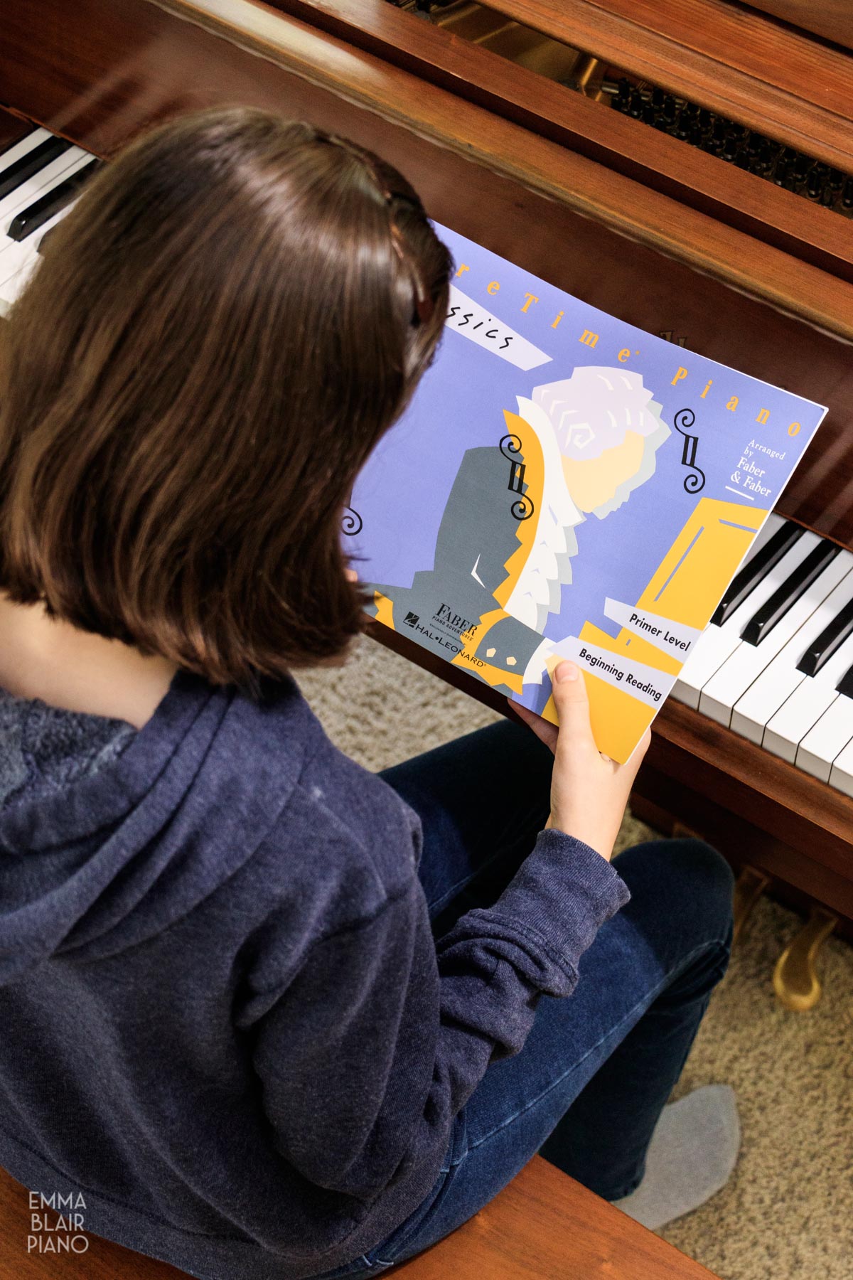 young girl holding a beginner piano book