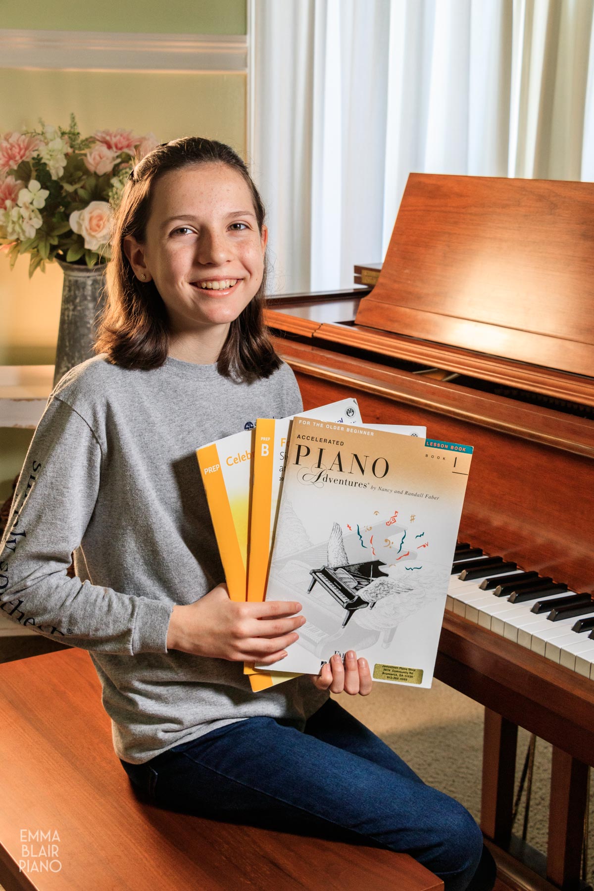 girl smiling and holding three beginner piano books