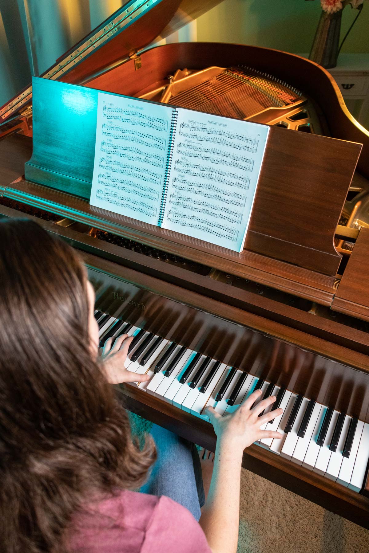 girl playing scales in octaves at a brown grand piano