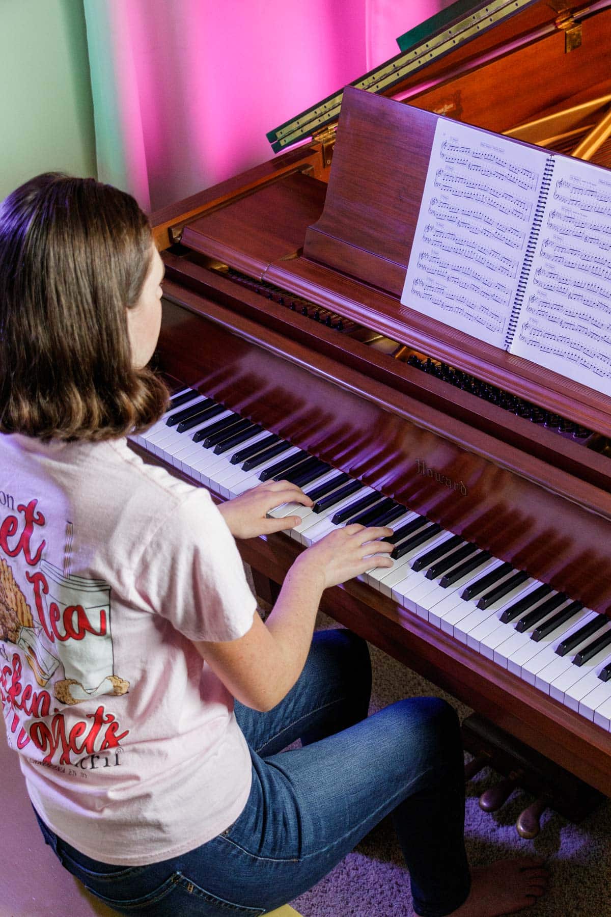 girl playing scales from a book at a piano