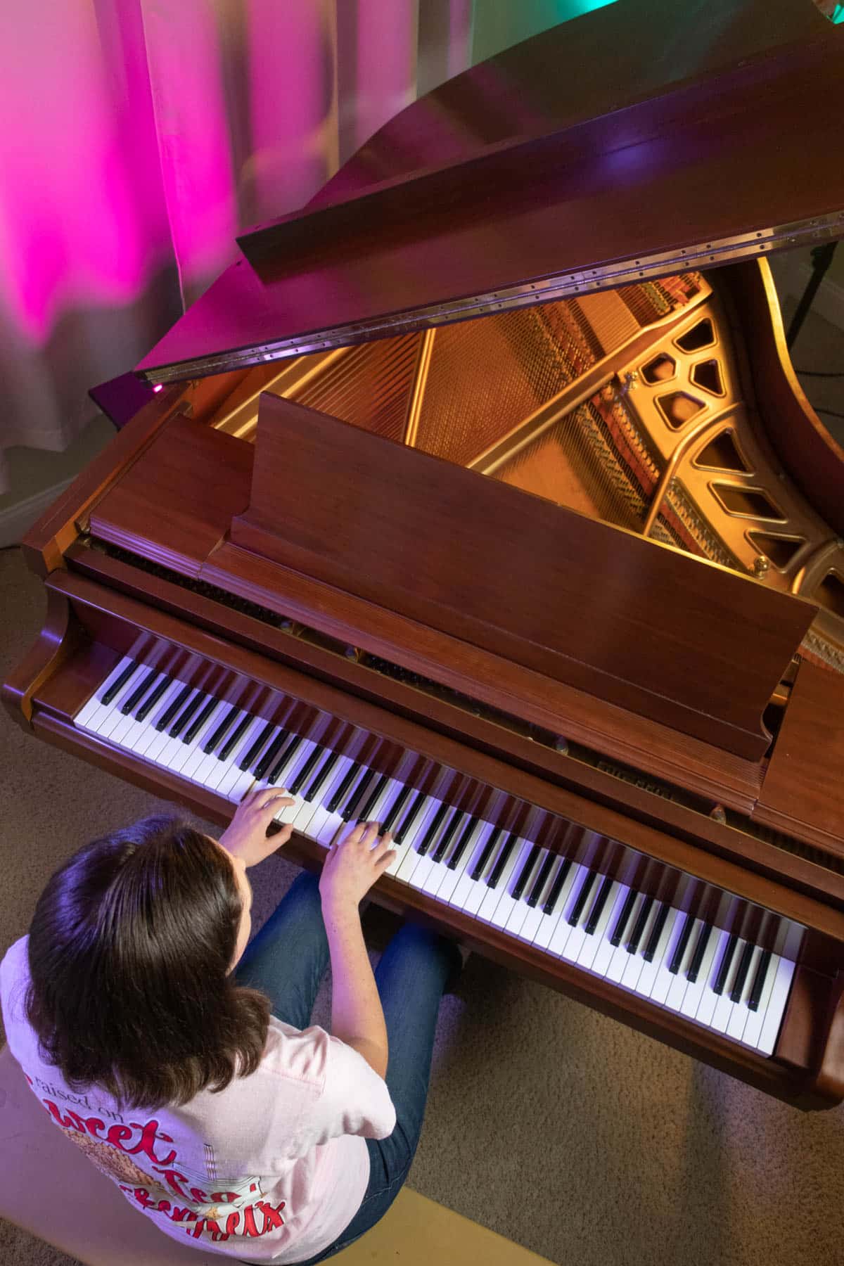 girl playing scales on a brown grand piano