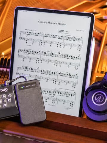 Bluetooth pedal, iPad, Apple Pencil, and headphones with a piano