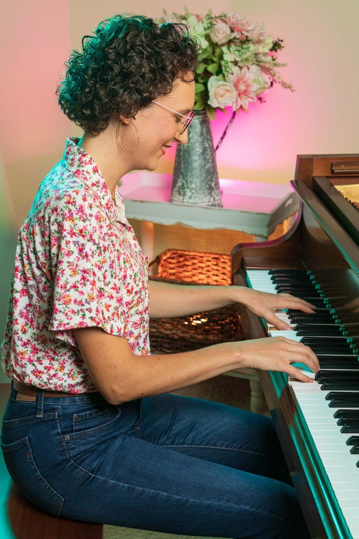 side view of Emma playing a brown grand piano.